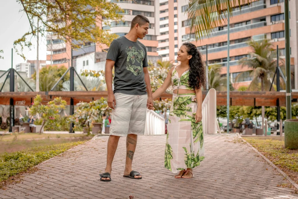 Casal jovem de mãos dadas caminhando em frente a prédios residenciais, perfil de quem compra o primeiro imóvel pelo Minha Casa Minha Vida